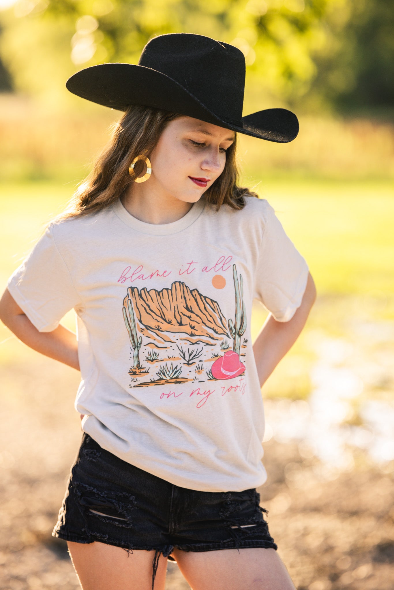 T-shirt with the text "Blame It All on My Roots," featuring a design that playfully highlights a love for country roots and style.