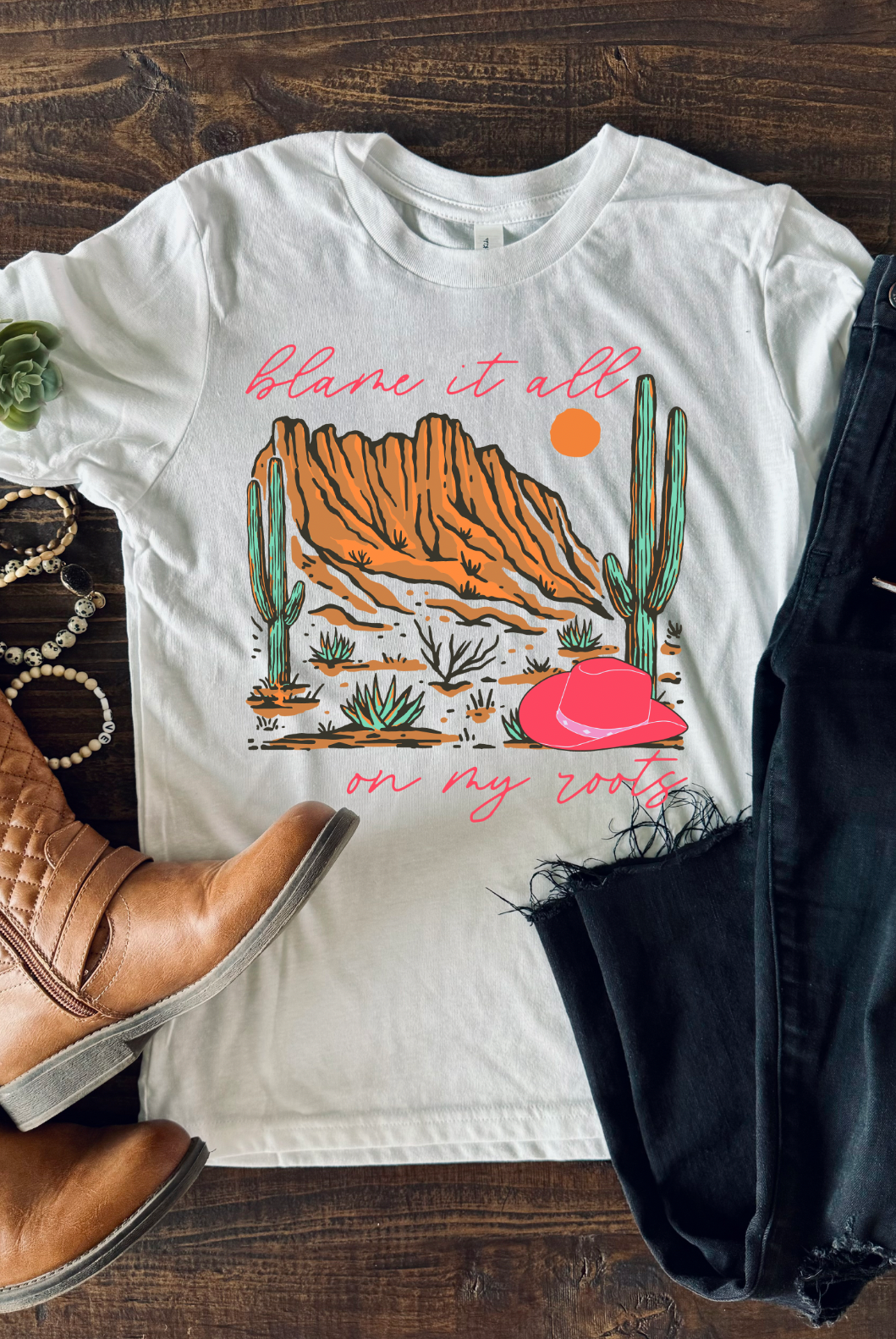 Cement Bella and Canvas T-shirt with the text "Blame It All on My Roots," featuring a design that playfully highlights a love for country roots and style.