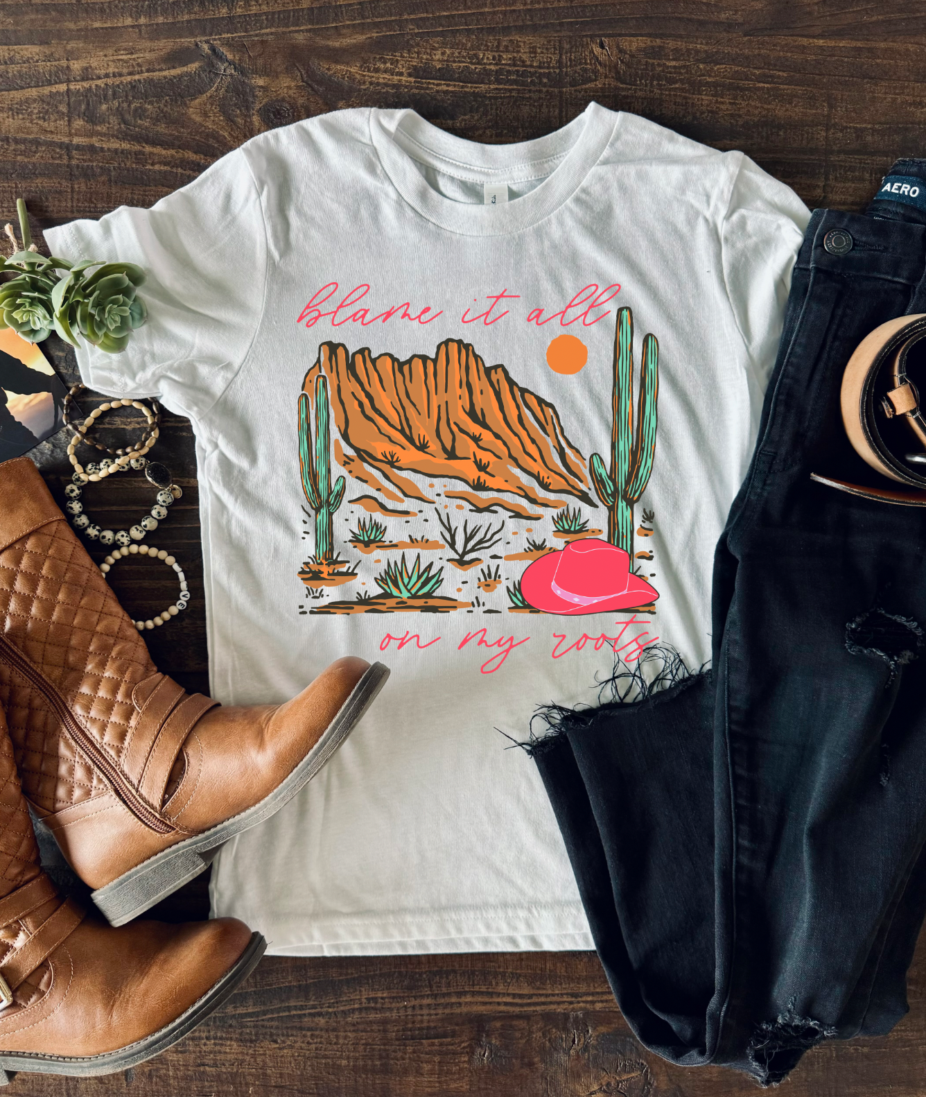 Cement Bella and Canvas T-shirt with the text "Blame It All on My Roots," featuring a design that playfully highlights a love for country roots and style.