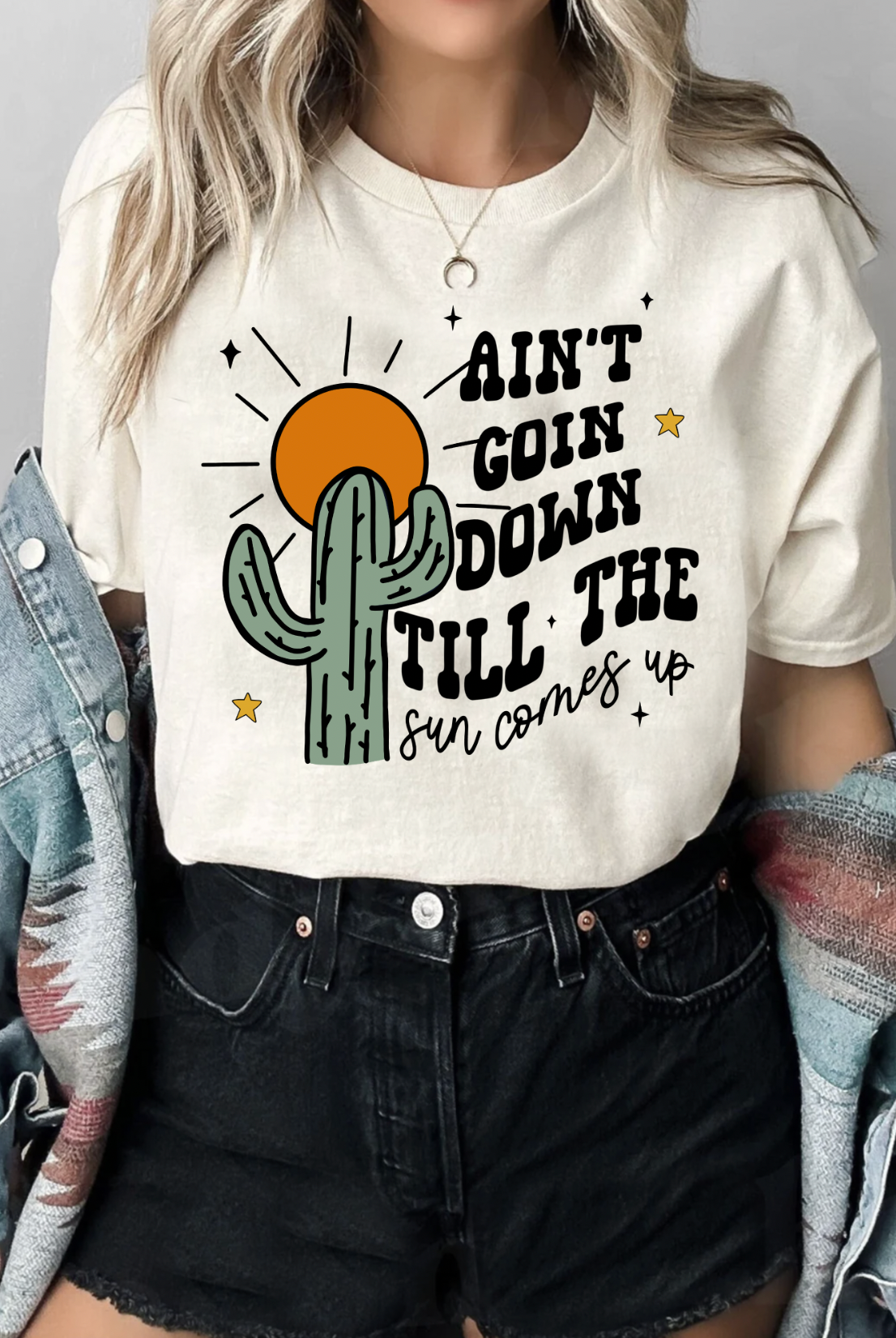 Soft Cream Colored Bella and Canvas Unisex Tshirt with Ain't Goin Down Till The Sun Comes Up on it. Handmade in TX. Flannel accessory.