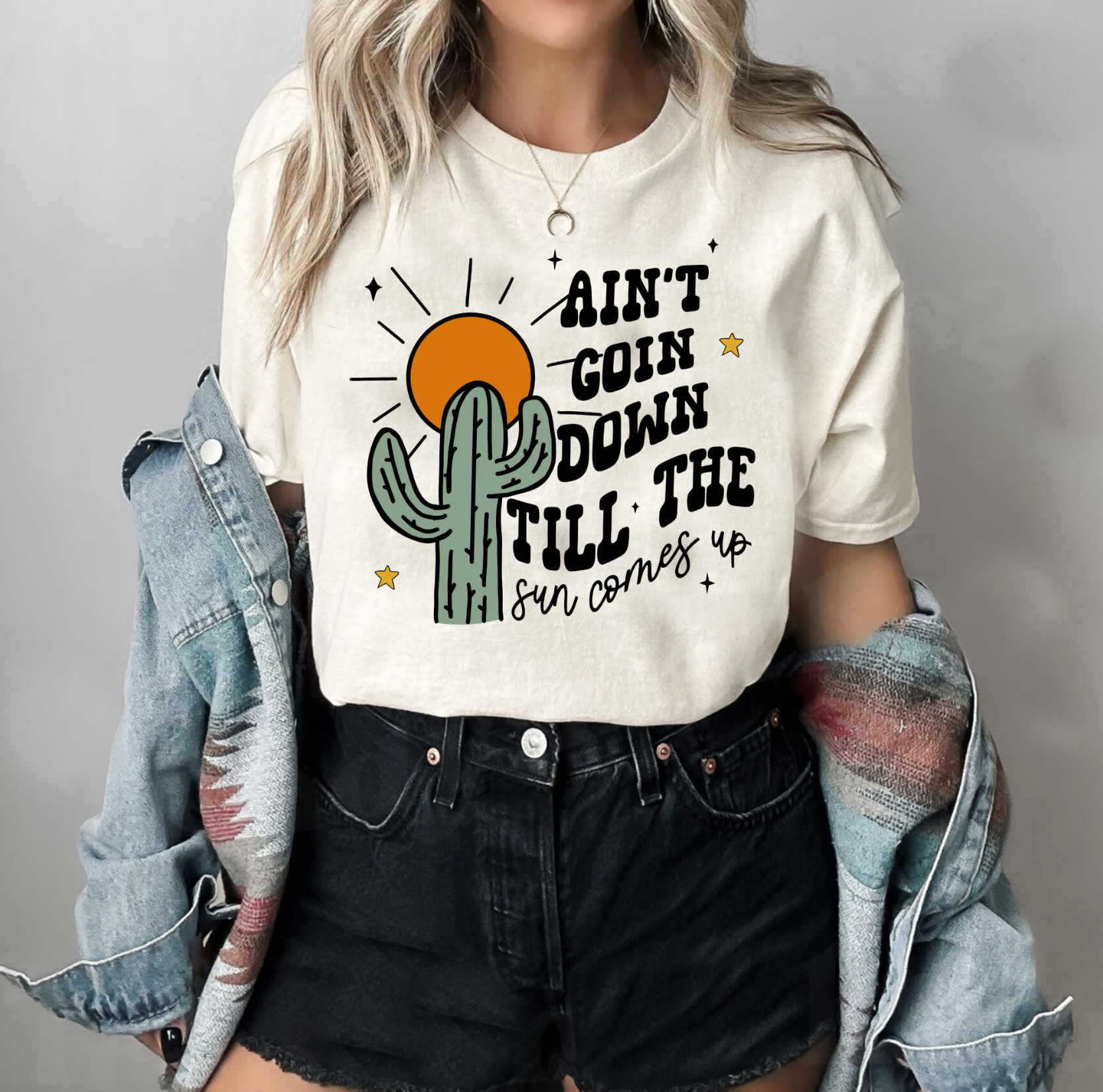 Soft Cream Colored Bella and Canvas Unisex Tshirt with Ain't Goin Down Till The Sun Comes Up on it. Handmade in TX. Flannel accessory.