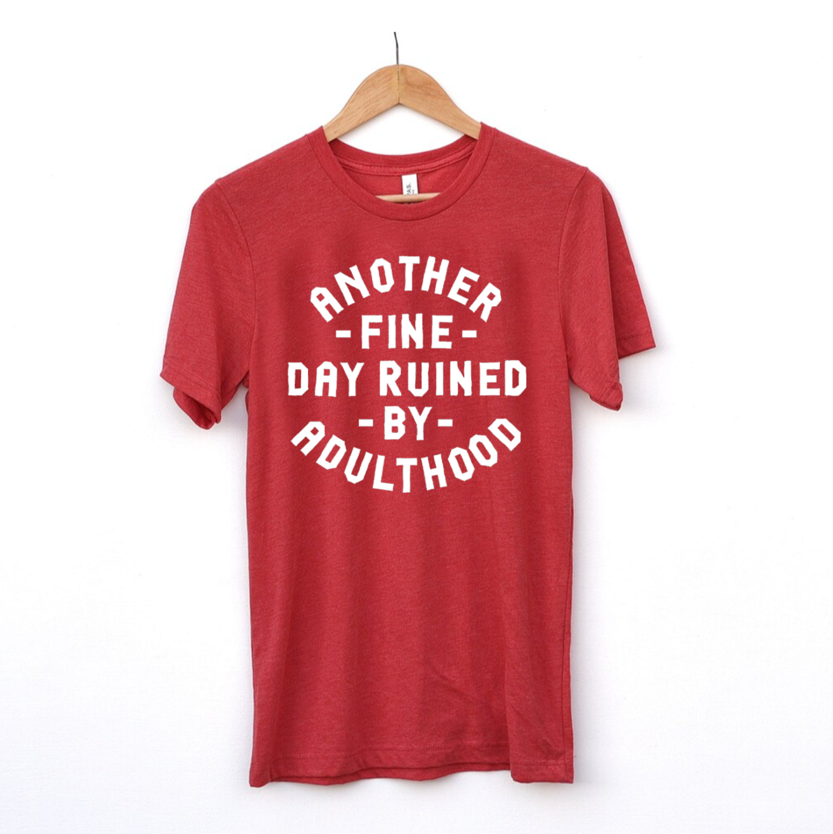 Bella + Canvas Heather Red t-shirt with the text "Another Fine Day Ruined by Adulthood," featuring a humorous and relatable design.