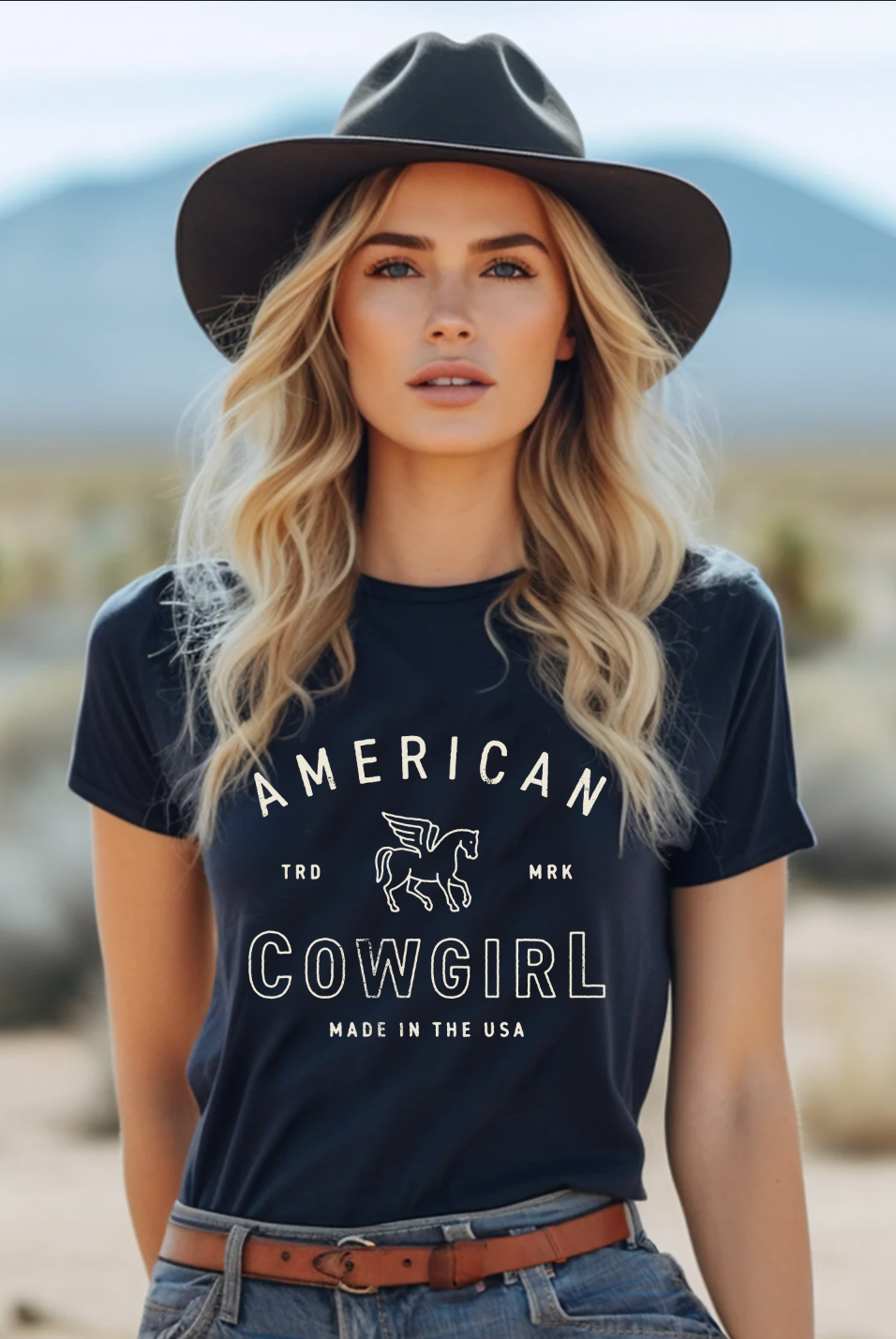 Black t-shirt with the text "American Cowgirl" in a western-style design, perfect for showcasing country pride and rodeo style.