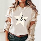 Cream colored soft shirt from Bella and Canvas, this shirt has a rustic star with Oklahoma written in cursive with an adorable heart.