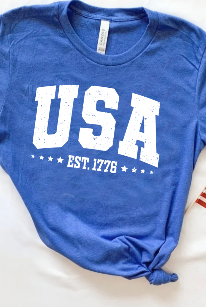 USA Est. 1776 with stars on a classic heathered blue Bella and Canvas tshirt. Americana 4th of July graphic tee.